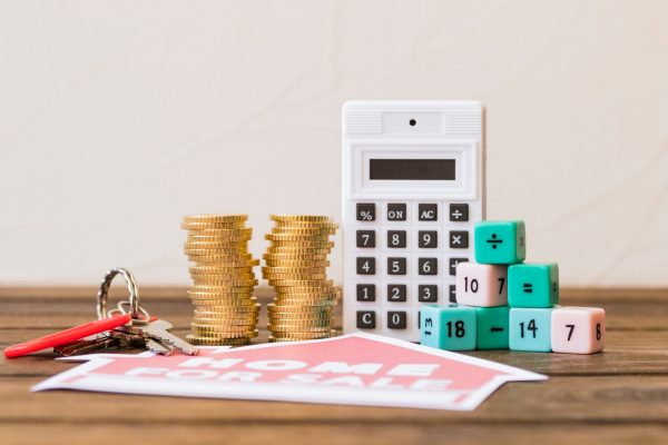 close-up-home-sale-icon-with-key-stacked-coins-calculator-math-blocks_23-2147863937